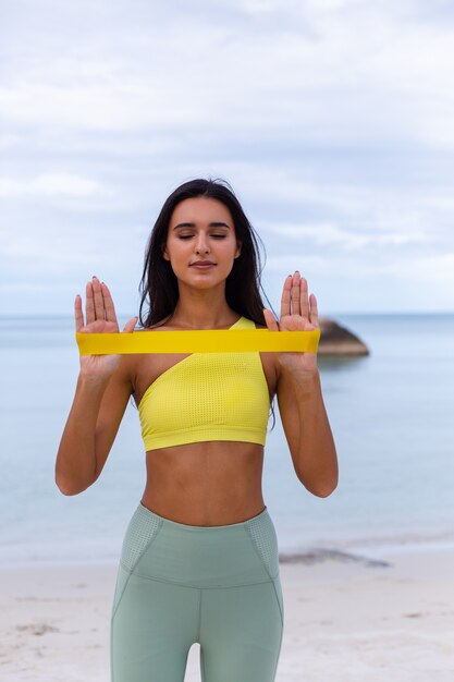 Atractiva mujer joven en ropa deportiva colorida en la playa