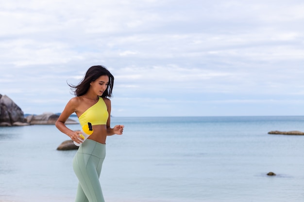 Atractiva mujer joven en ropa deportiva colorida en la playa