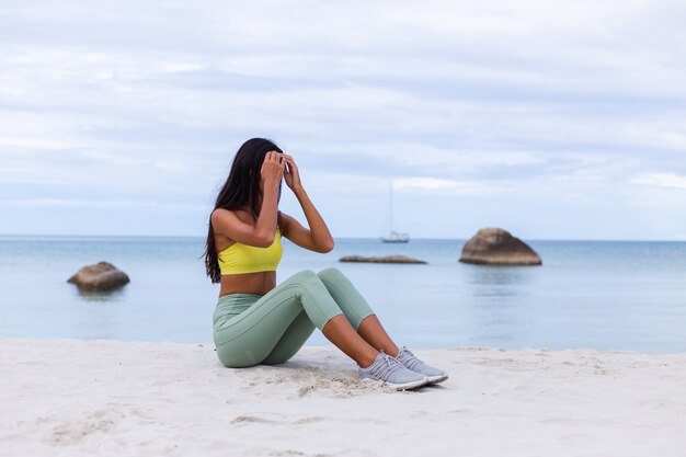 Atractiva mujer joven en ropa deportiva colorida en la playa