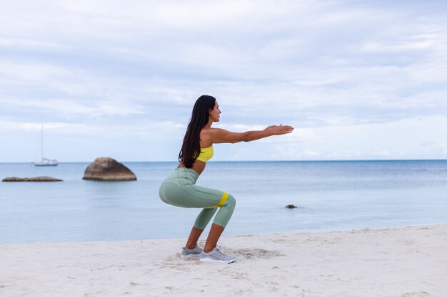 Atractiva mujer joven en ropa deportiva colorida en la playa