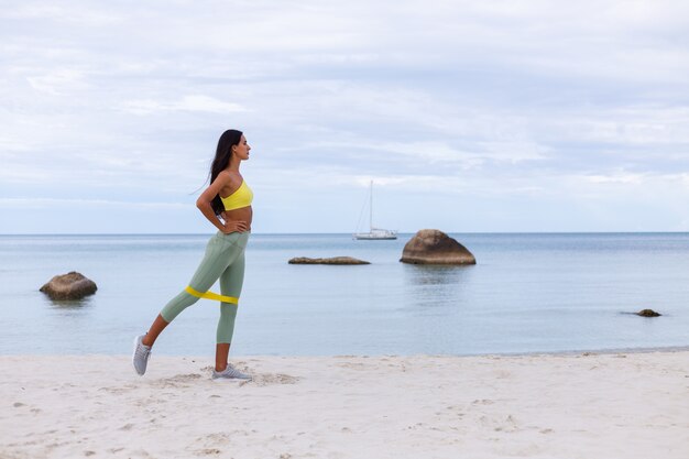 Atractiva mujer joven en ropa deportiva colorida en la playa