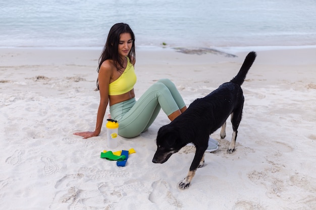 Atractiva mujer joven en ropa deportiva colorida en la playa