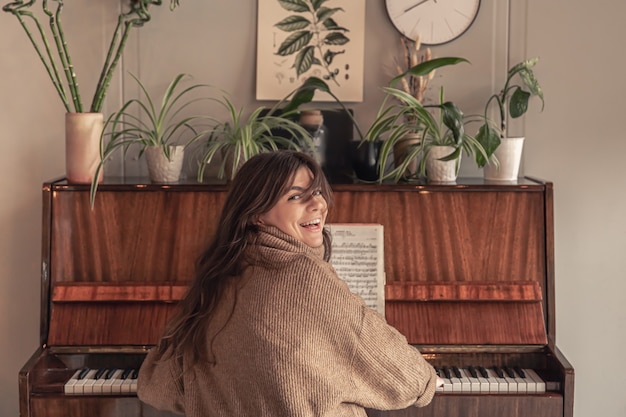 Foto gratuita atractiva mujer joven tocando el piano en casa