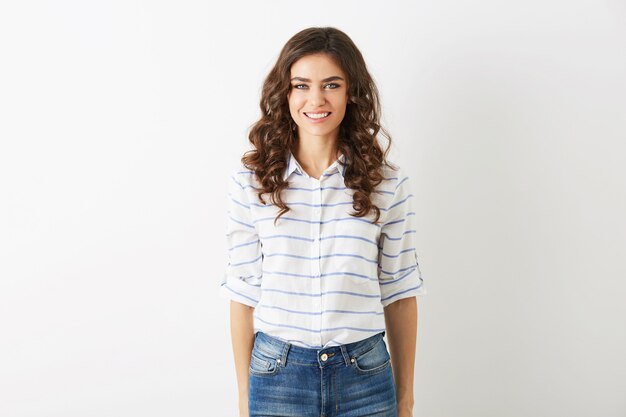 Atractiva mujer joven vestida con estilo casual de estudiante, camisa y jeans, cabello rizado, sonriente, hermosa modelo aislada, dientes blancos, cara bonita