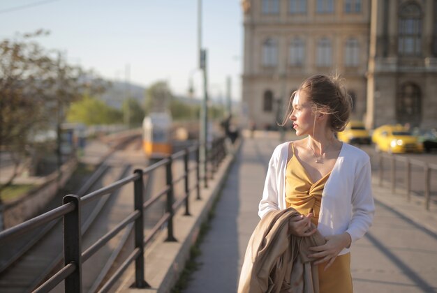 Atractiva mujer joven con un vestido amarillo caminando por las calles bajo la luz del sol en Hungría