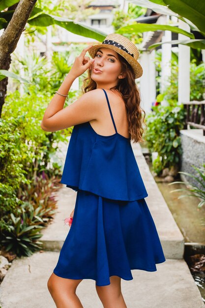 Atractiva mujer joven en vestido azul y sombrero de paja