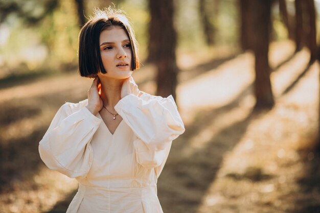Atractiva mujer joven en vestido blanco en el bosque
