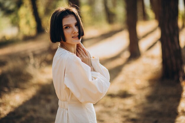 Atractiva mujer joven en vestido blanco en el bosque