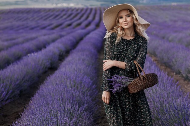 Atractiva mujer joven en vestido y sombrero en lavanda presentada