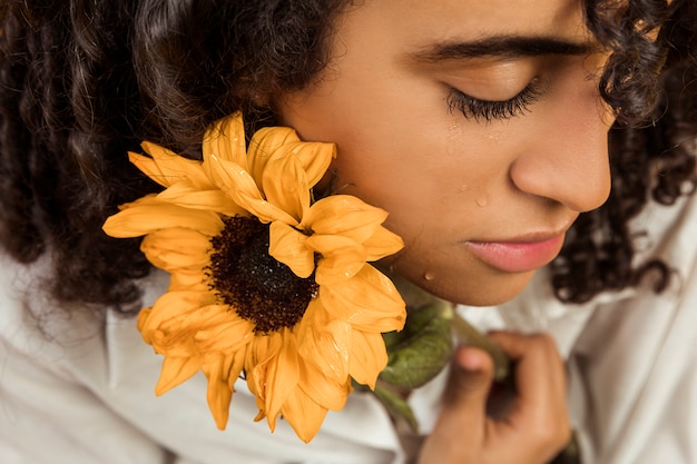 Atractiva mujer llorona étnica con flor.