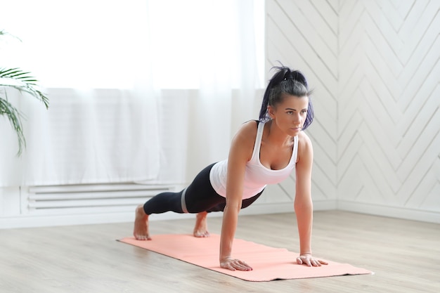 Atractiva mujer morena haciendo yoga en casa.