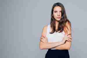 Foto gratuita atractiva mujer morena sostiene sus brazos cerca de su rostro aislado sobre fondo blanco.