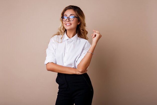 Atractiva mujer de negocios exitosa con sincera sonrisa mirando. Profesor o empleado. Pared beige