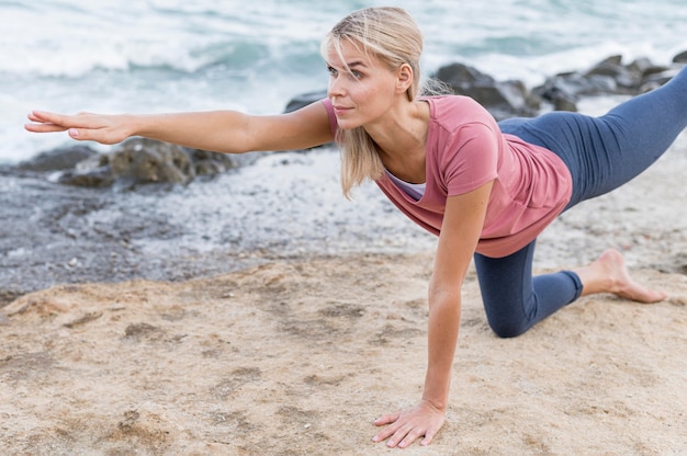 Atractiva mujer rubia haciendo yoga al aire libre