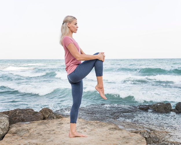 Atractiva mujer rubia haciendo yoga al aire libre
