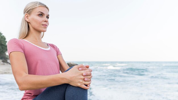 Atractiva mujer rubia haciendo yoga al aire libre