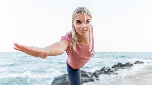 Atractiva mujer rubia haciendo yoga al aire libre