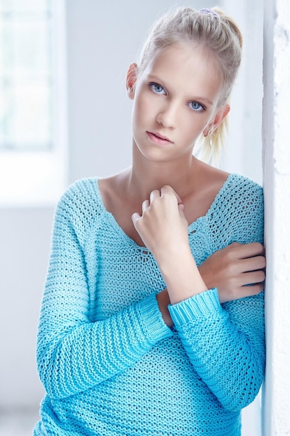 Atractiva mujer rubia de ojos azules con chaqueta azul. Brazos cruzados.