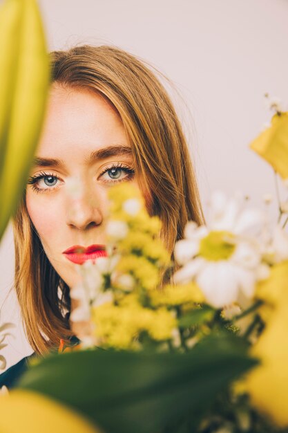 Atractiva mujer segura detrás de las flores