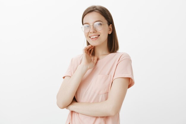 Atractiva mujer sonriente con gafas mirando soñadora