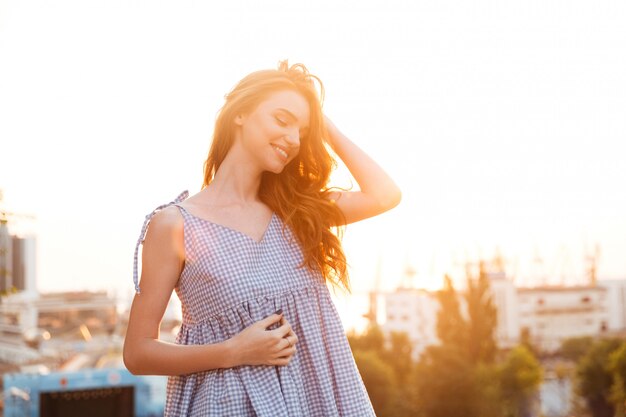 Atractiva mujer sonriente de jengibre en vestido posando con los ojos cerrados