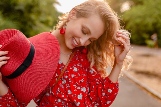 Atractiva mujer sonriente rubia elegante en traje de moda de verano de sombrero rojo de paja y blusa