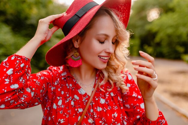 Atractiva mujer sonriente rubia elegante en traje de moda de verano de sombrero rojo de paja y blusa