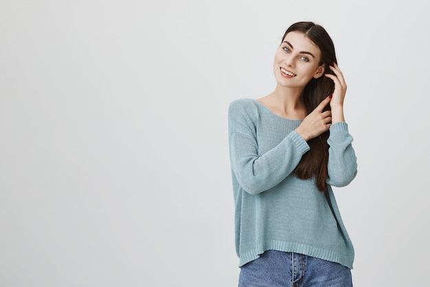 Atractiva mujer tierna tocando el cabello suavemente, sonriendo