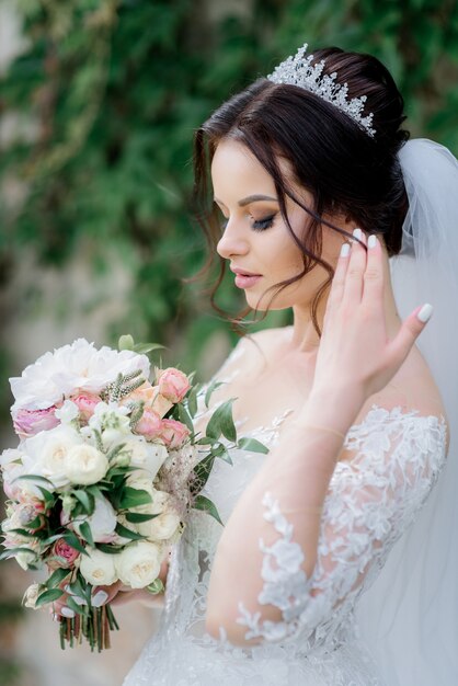 Atractiva novia en corona con hermoso ramo de novia hecho de eustomas blancas y rosas rosadas