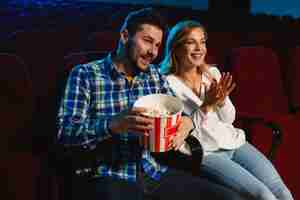 Foto gratuita atractiva pareja caucásica joven viendo una película en una sala de cine, una casa o un cine. luce expresivo, asombrado y emocionado. sentarse solo y divertirse. relación, amor, familia, fin de semana.