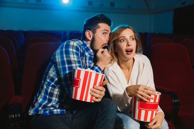 Atractiva pareja caucásica joven viendo una película en una sala de cine, una casa o un cine.