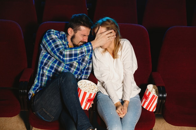 Atractiva pareja caucásica joven viendo una película en una sala de cine, una casa o un cine.