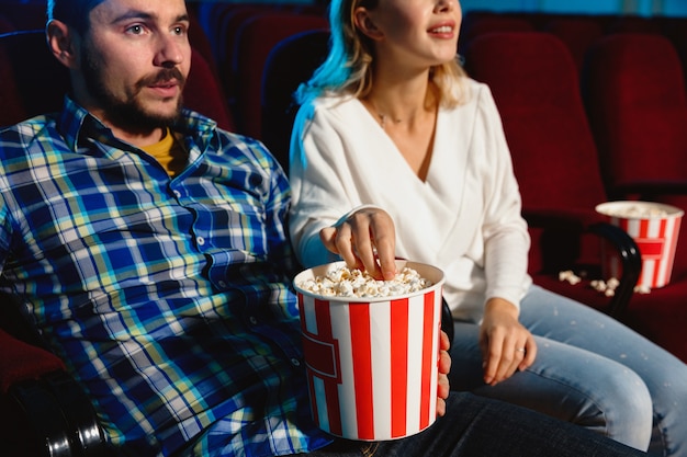 Atractiva pareja caucásica joven viendo una película en una sala de cine, una casa o un cine.