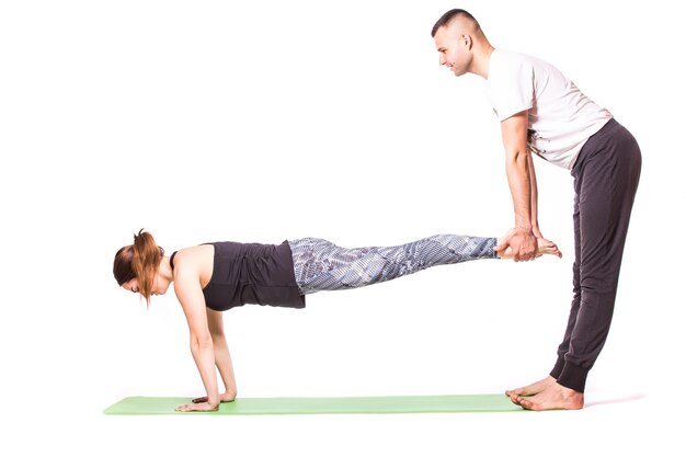 Atractiva pareja haciendo yoga juntos sobre fondo blanco.