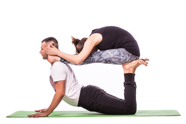 Atractiva pareja haciendo yoga juntos sobre fondo blanco.