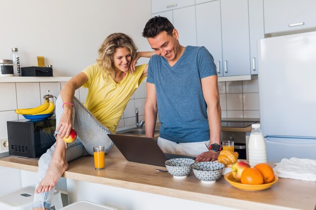 Atractiva pareja joven de hombre y mujer cocinando el desayuno juntos en la mañana en la cocina