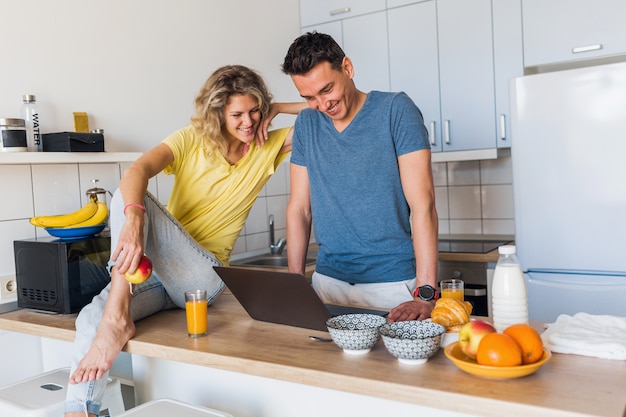 Atractiva pareja joven de hombre y mujer cocinando el desayuno juntos en la mañana en la cocina