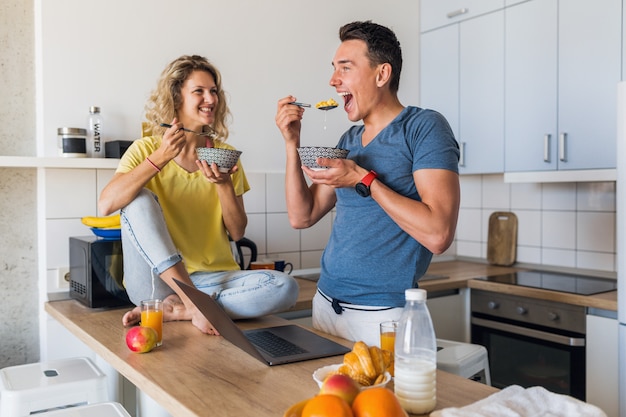 Atractiva pareja joven de hombre y mujer desayunando juntos en la mañana en la cocina