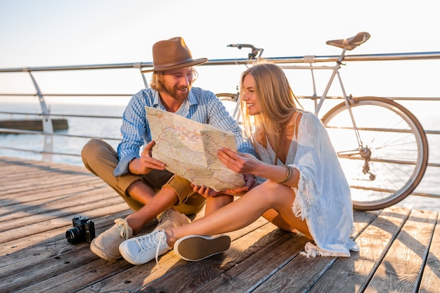 Atractiva pareja sonriente feliz viajando en verano por mar en bicicleta