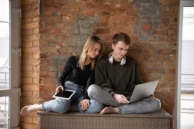 Atractiva pareja sorprendida y asombrada usando dispositivos juntos