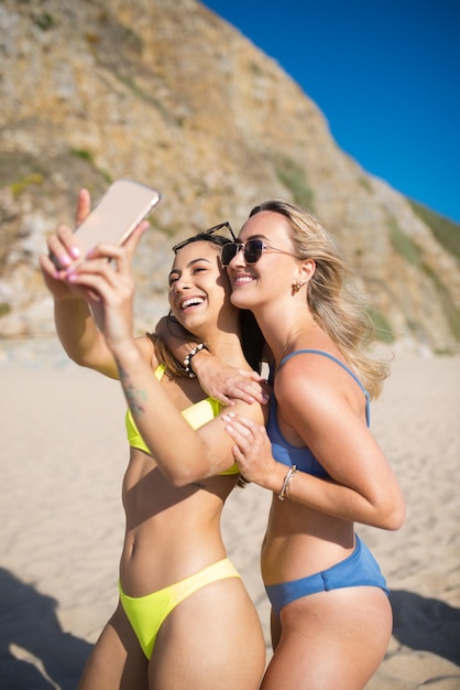 Atractivas amigas haciendo selfie en fiesta en la playa