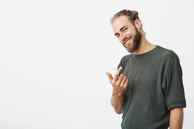 Atractivo cantante famoso haciendo señas con el dedo y sonriendo suavemente