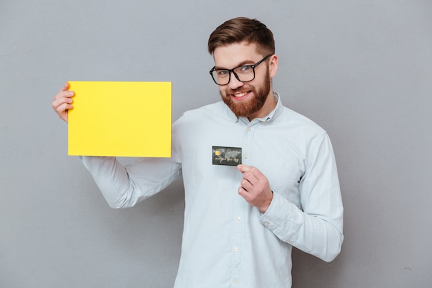 Foto gratuita atractivo empresario barbudo con papel en blanco y tarjeta de débito