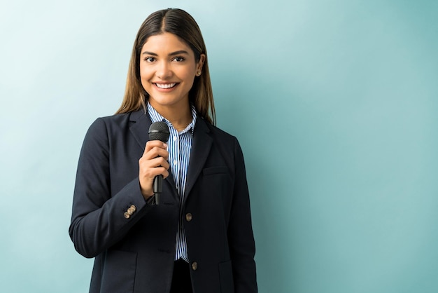 Atractivo y exitoso profesional de negocios con micrófono contra fondo de color