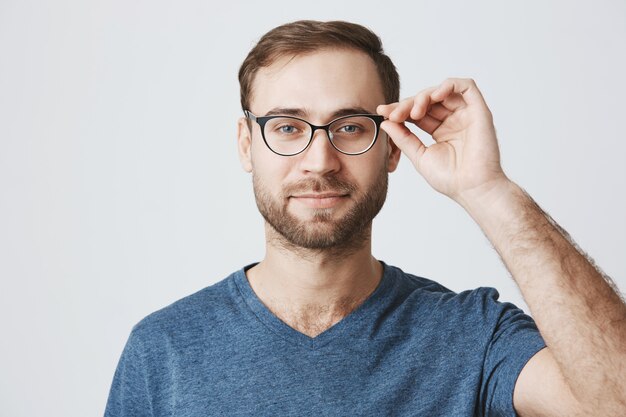 Foto gratuita atractivo hombre barbudo recogiendo gafas en la tienda de óptica