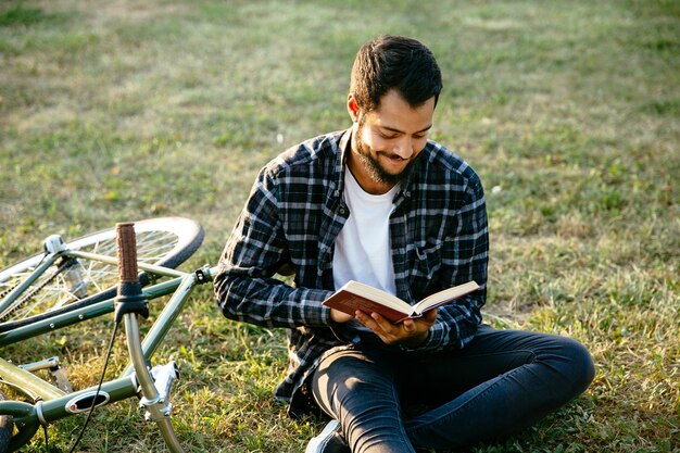 Atractivo hombre barbudo sonriente leyendo un libro interesante, pasar tiempo