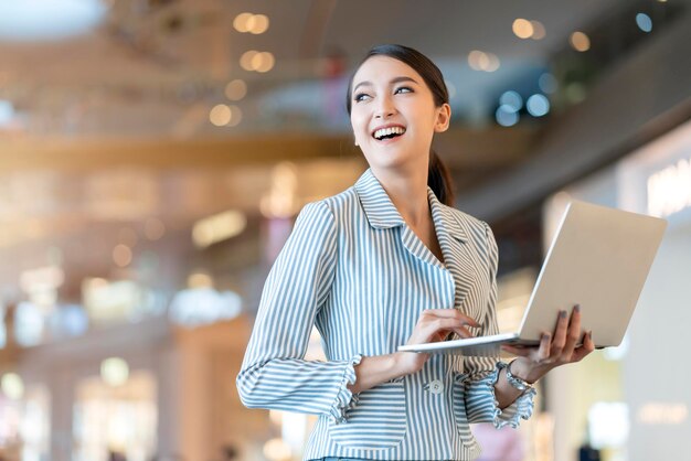 atractivo, inteligente, hermoso, asiático, mujer, bien vestido, comunicación, teléfono inteligente, con, alegre, y, confiado, desenfoque, espacio público, plano de fondo