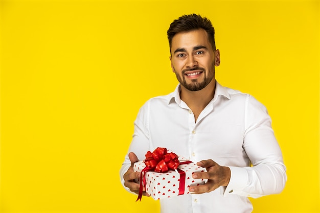 Atractivo joven europeo en camisa blanca tiene un regalo