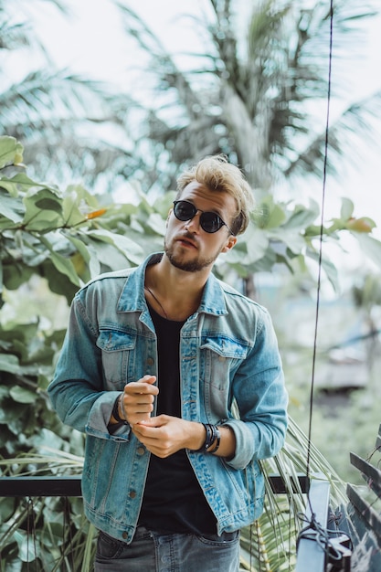 atractivo joven posando en un lugar tropical, sobre un fondo de palmeras y vegetación