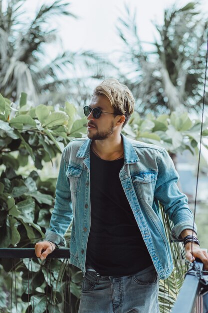 atractivo joven posando en un lugar tropical, sobre un fondo de palmeras y vegetación